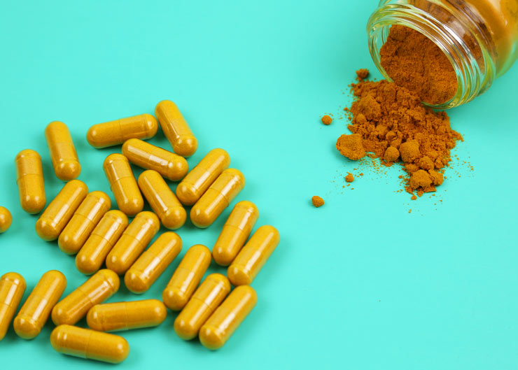 Turmeric capsules on teal background